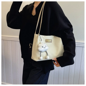 Detail of off-white tote bag featuring waffle texture fabric and a cute plush cloud charm