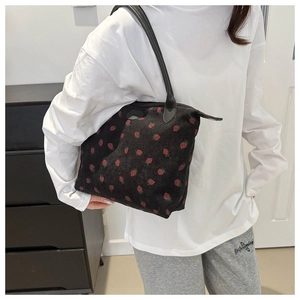 Detail of black corduroy shoulder bag featuring an all-over strawberry floral print