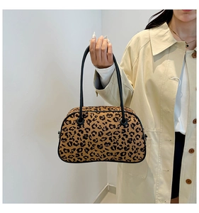 Detail of leopard print handbag texture and black cylindrical handle on a beige trench coat