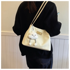 Detail of beige waffle textured tote bag featuring a cute cloud plush charm and metal logo
