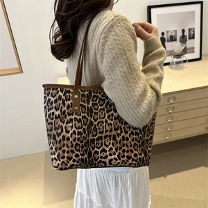 Chic leopard print canvas tote bag with brown leather straps shown on a female model