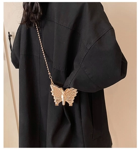 Detailed view of a gold butterfly mini evening bag with rhinestones on a black coat