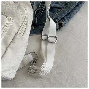 Detail of adjustable silver buckles and white nylon strap on a stylish crossbody bag