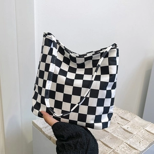 Détail du sac fourre-tout en toile à damier noir et blanc avec texture douce et bandoulière