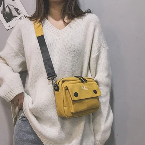 Detail of yellow canvas crossbody bag featuring DCY graphic and bicolor woven shoulder strap