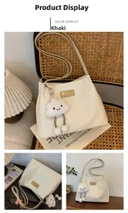 Detail of khaki waffle-weave tote bag with plush cloud charm on vintage rattan chair