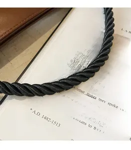 Close-up of black braided rope handle on a brown leather retro commute tote bag