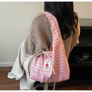 Detail of pink and blue checkered canvas hobo bag with red tomato patch and drawstrings