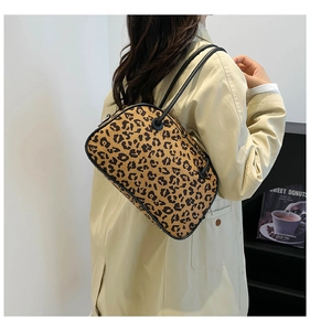 Close-up of leopard print shoulder bag with black leather straps and textured fabric finish
