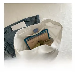 Top view of large white canvas tote bag showing spacious interior with tablet and books