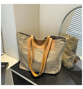 Detail view of the large canvas tote bag with brown leather handles on a minimal cabinet