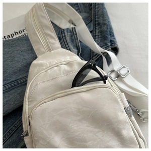Close-up of white wrinkled texture chest bag with zippers and adjustable wide strap