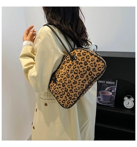Detail view of the leopard print handbag with slim black straps and rectangular structure
