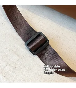 Close-up of adjustable dark brown woven shoulder strap with black plastic buckle detail