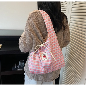 Detail of blue plaid canvas tote bag with drawstring closure and handmade brand label