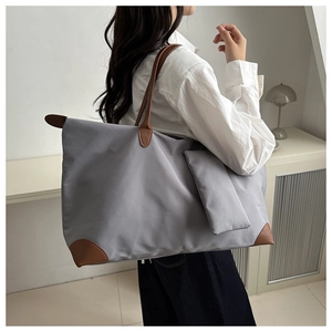 Detail of grey nylon tote bag with brown leather handles worn by a female model