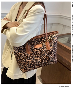 Detail of leopard print tote bag with brown leather handles and textured fabric finish