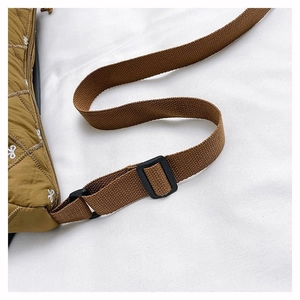 Detail der olivgrünen gesteppten Nylontasche mit Schleifenstickerei und Gurt