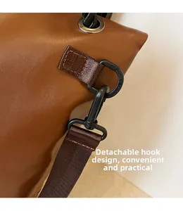 Detail of the detachable black metal hook design and brown nylon strap on the shoulder bag