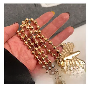 Macro detail of high-shine gold butterfly metal hardware and beaded chain for evening bag