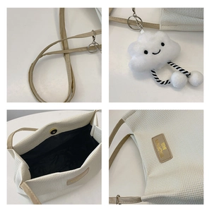 Detail of off-white waffle texture tote bag with leather strap and cloud charm