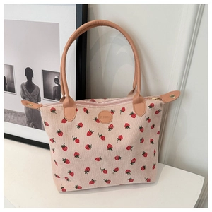 Detailed close-up of corduroy tote bag featuring red strawberry prints and leather logo