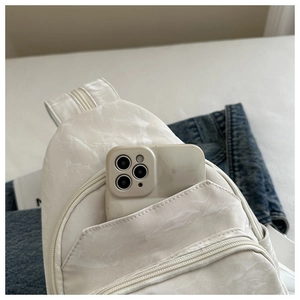 Detail of off-white crossbody bag with marble texture showing phone storage capacity