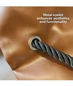 Detail of metal eyelets and thick spiral woven rope handle on brown leather handbag