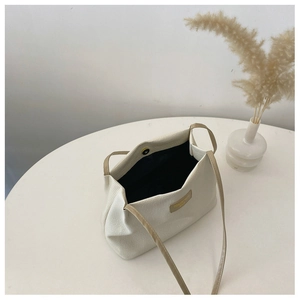 Detail of white textured tote bag featuring leather straps and magnetic buckle closure