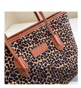 Close-up of leopard print canvas tote with brown leather trim and detailed stitching