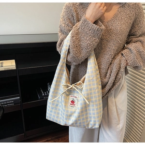 Detail of yellow and blue checkered canvas tote bag with drawstring bow and tomato patch