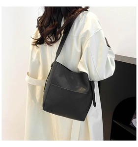 Detail of black pebbled leather bucket bag showing its slouchy texture and wide strap