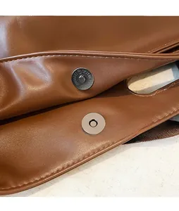 Detailed close-up of the silver magnetic buckle on a brown leather vintage tote bag