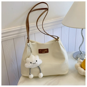 Detail of cream textured tote bag featuring brown leather straps and cloud charm