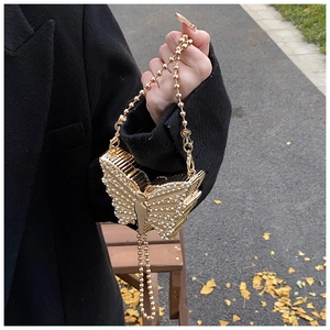 Close-up of golden butterfly evening bag with sparkling rhinestones and chain strap