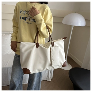 Detail of white nylon tote with brown leather trim and matching small hanging pouch