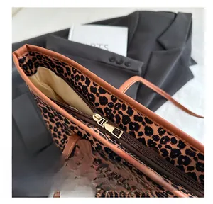 Close-up of metal zipper detail on leopard print tote bag with brown leather trim