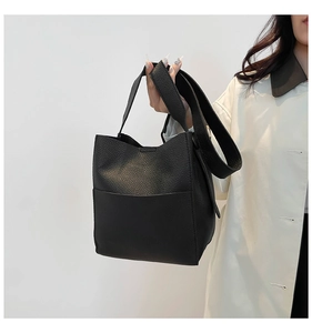 Close-up of black litchi pattern leather bucket bag with wide shoulder strap