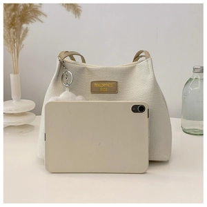 Detail showing white waffle texture tote bag with leather strap and cloud charm pendant