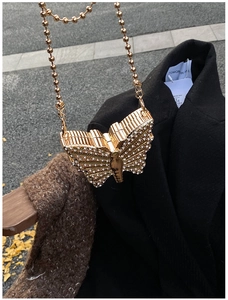 Close-up of golden butterfly evening bag with sparkling rhinestones and ball chain