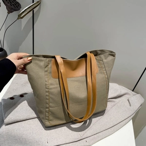 Large khaki canvas tote bag with brown leather handles and orange contrast stitching detail