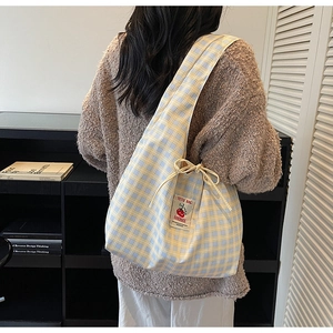 Detail of blue and yellow plaid canvas tote bag with side tomato embroidery label