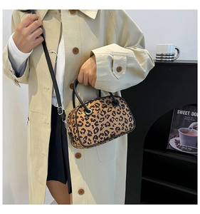 Close-up of leopard print bowling bag with black round handles and silver hardware