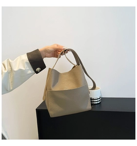 Close-up of taupe litchi grain leather bucket bag with wide handle and side pocket