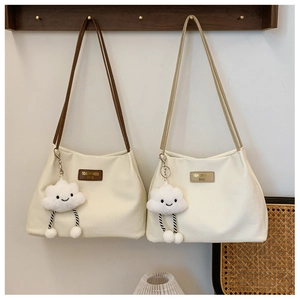 Detail of waffle texture tote bag with brown leather logo and cute cloud plush charm