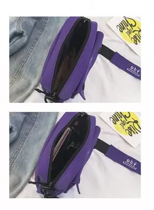 Detail view of purple canvas shoulder bag interior with zippered pocket and chain strap