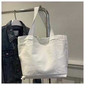 Detail of white canvas tote bag with multiple exterior pockets and durable texture