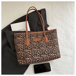 Detail of leopard print tote bag with brown handles resting on a black blazer