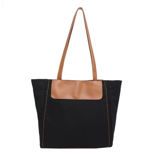 Large black canvas tote bag with brown leather handles and orange contrast stitching detail
