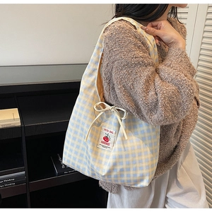 Detail of blue and yellow plaid canvas tote with cherry embroidery and drawstring bow